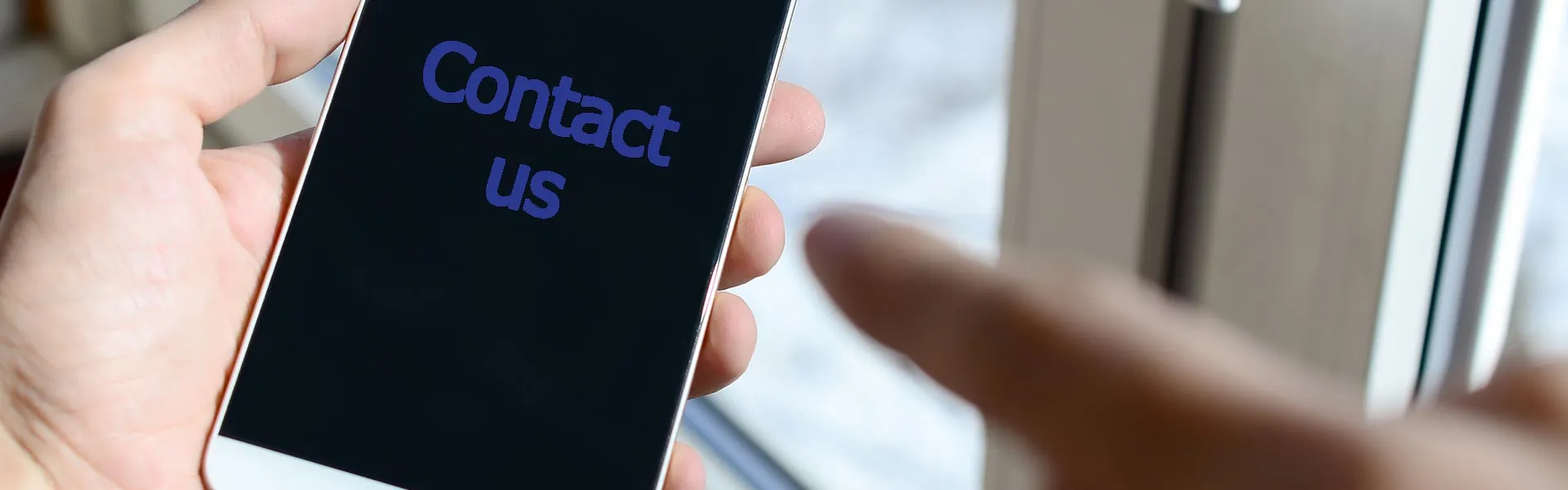 Hand holding a smartphone with the words Contact us on the screen